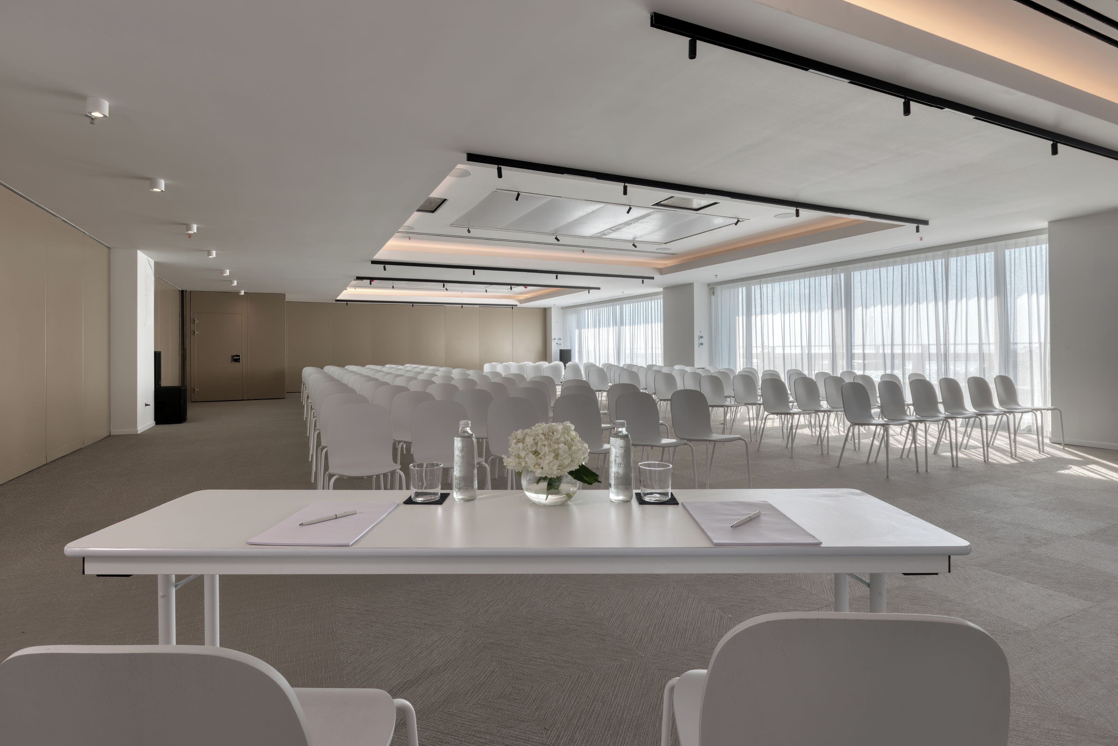 Un salón de conferencias con una larga mesa, sillas y un amplio ventanal.
