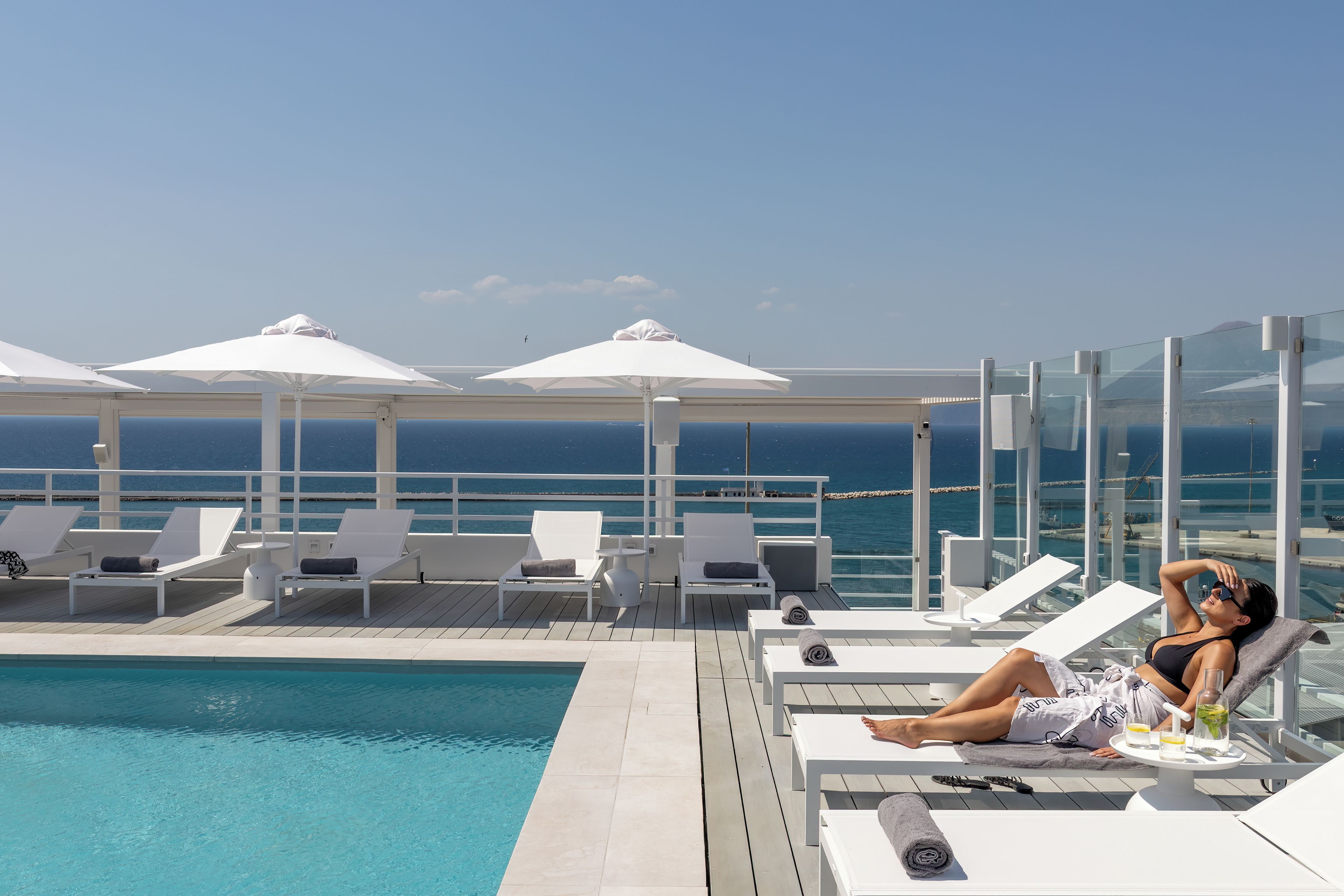A poolside area with lounge chairs and umbrellas, overlooking a body of water.