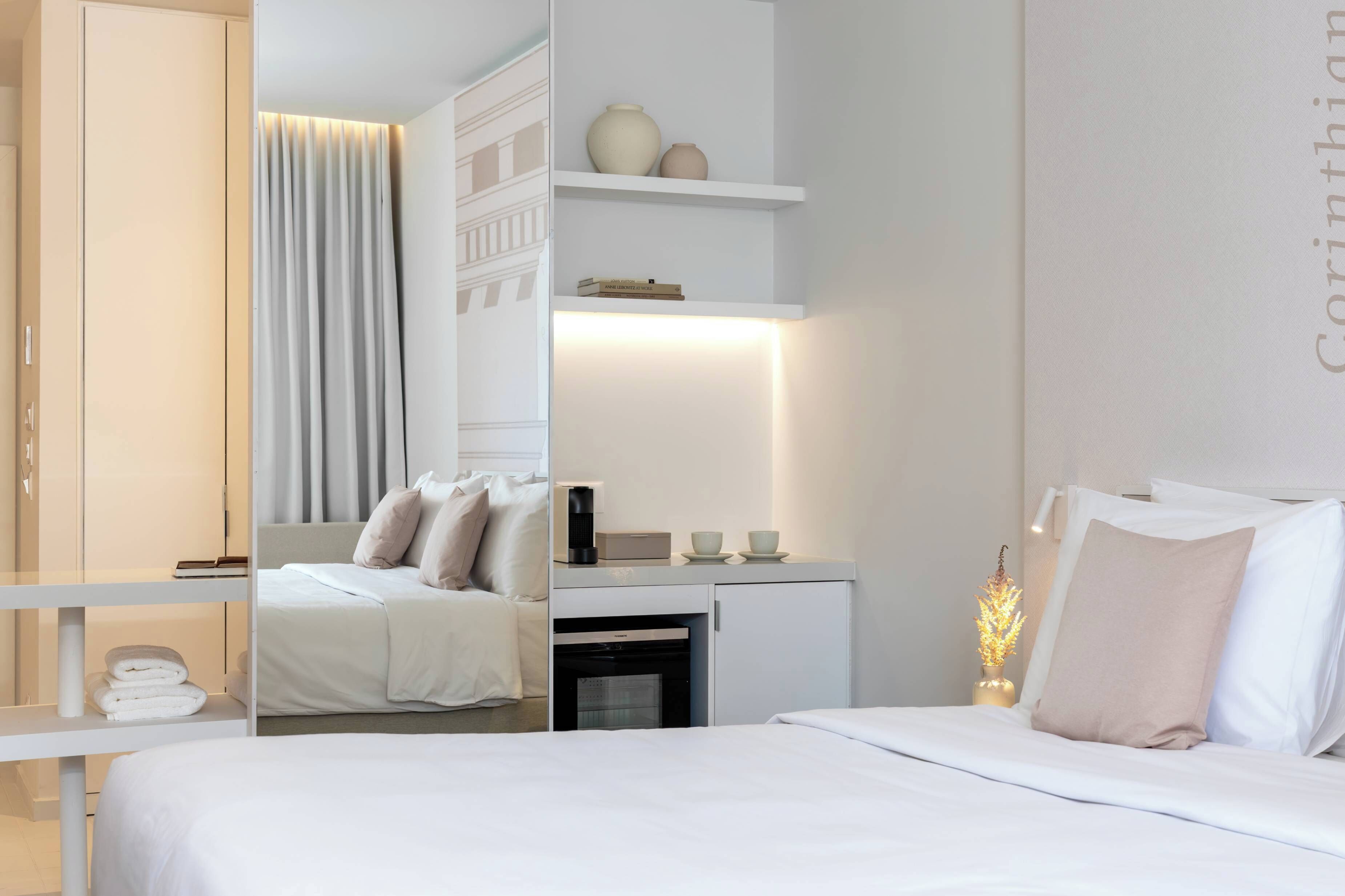 A modern hotel room with a bed, bedside table, and a built-in wardrobe.