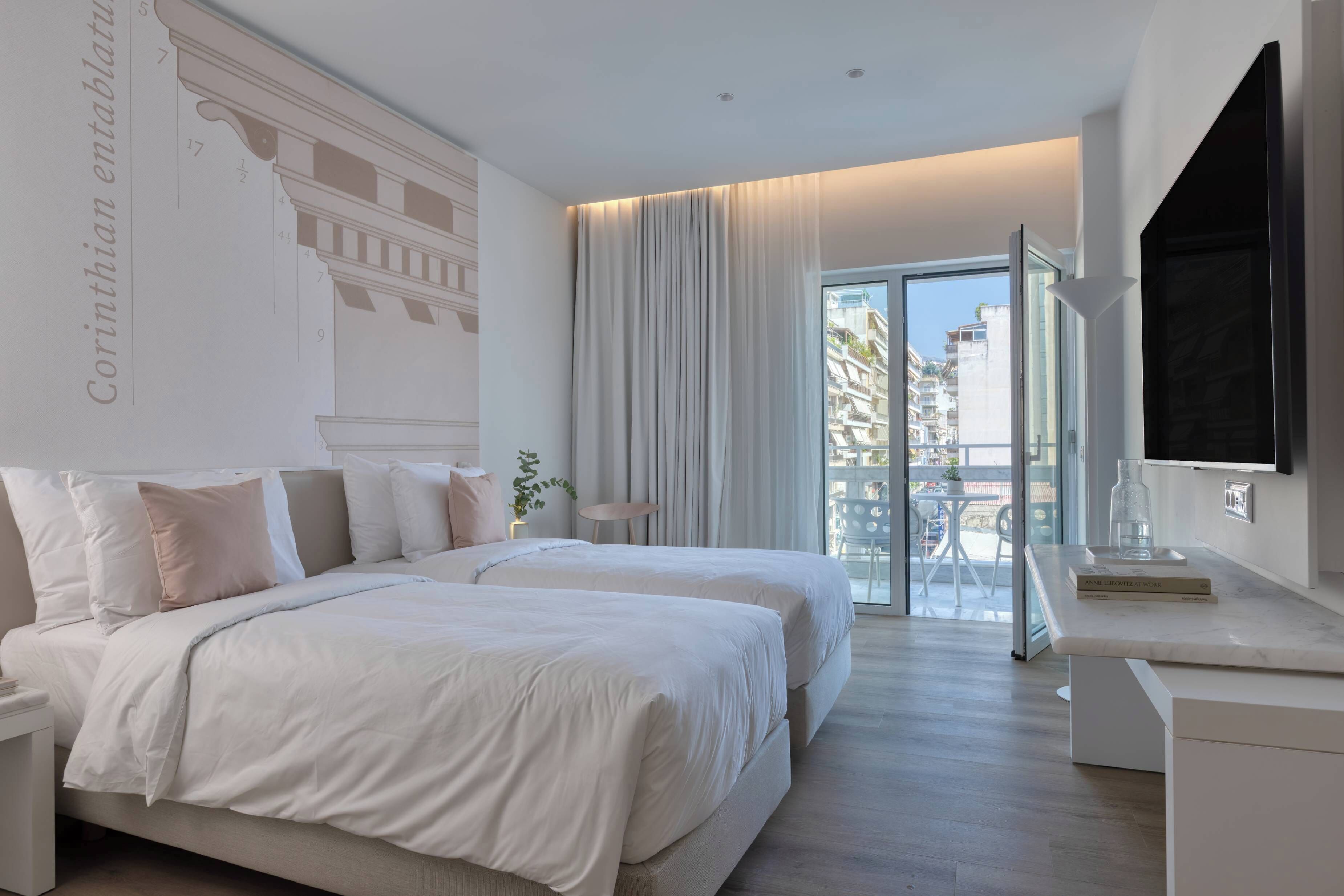 Habitación de hotel con una cama grande, un escritorio, un televisor y un balcón con vistas a edificios.