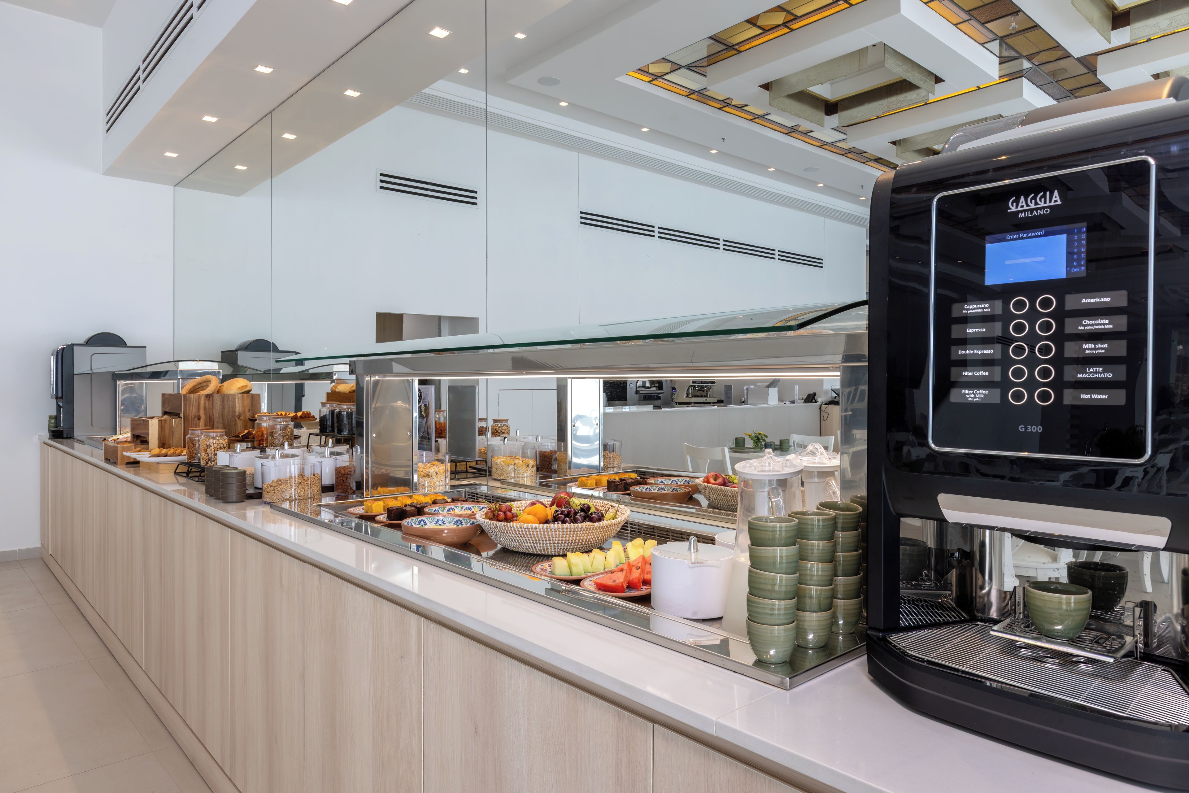A modern coffee station with a digital coffee machine and a variety of breakfast items.