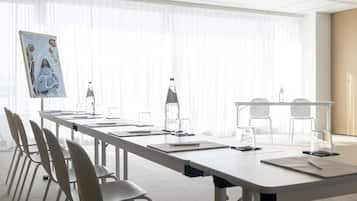 A conference room with a long table, chairs, and a projector screen.