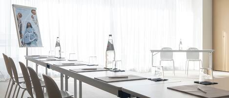A conference room with a long table, chairs, and a projector screen.