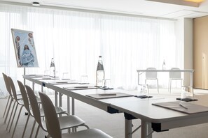 A conference room with a long table, chairs, and a projector screen. - Mercure Patras Astir (Patras)