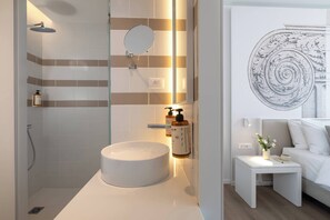 A modern bathroom with a round sink, a handheld showerhead, and a wall-mounted mirror. - Mercure Patras Astir (Patras)