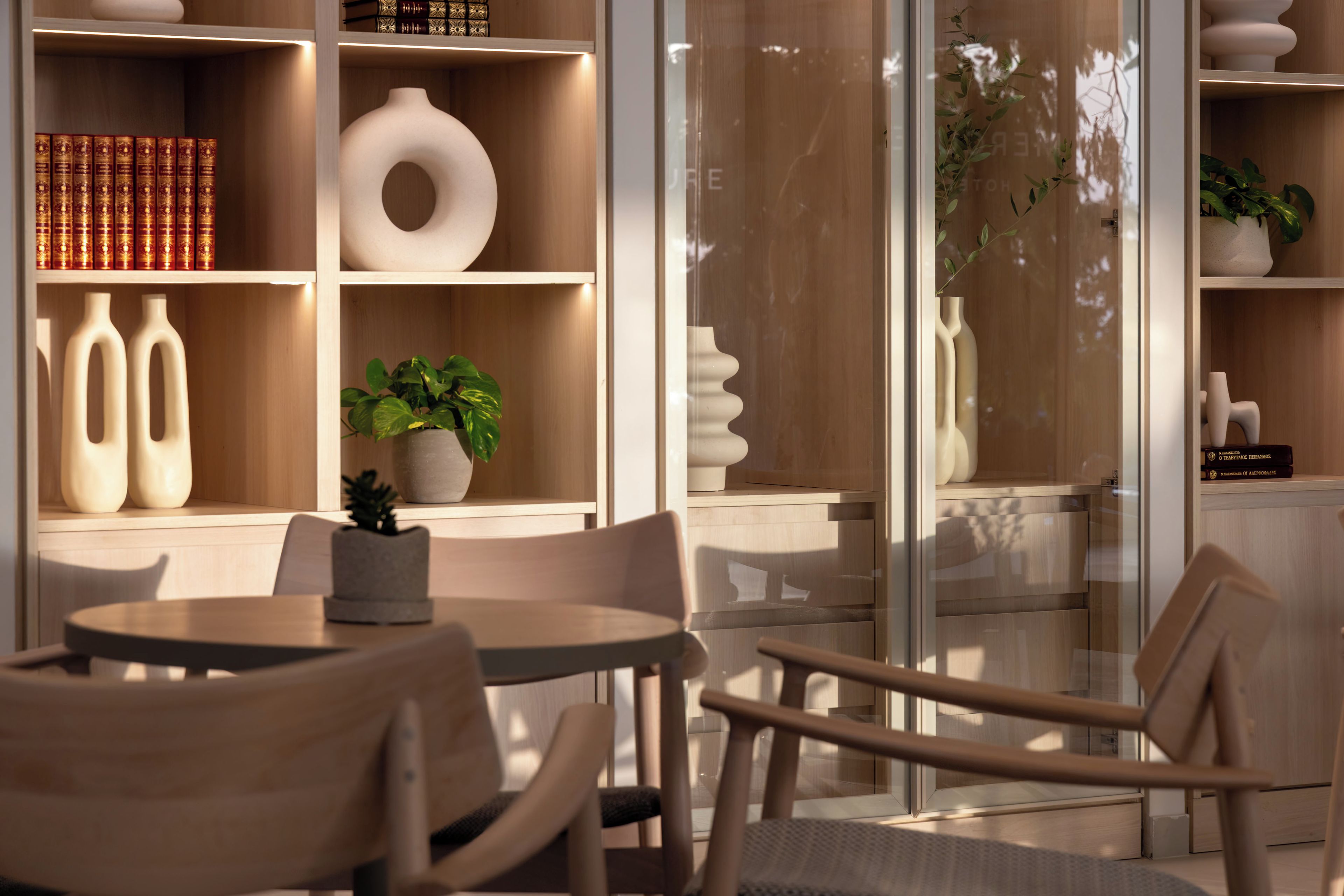 A modern interior with a round table, chairs, and a bookshelf with decorative items.