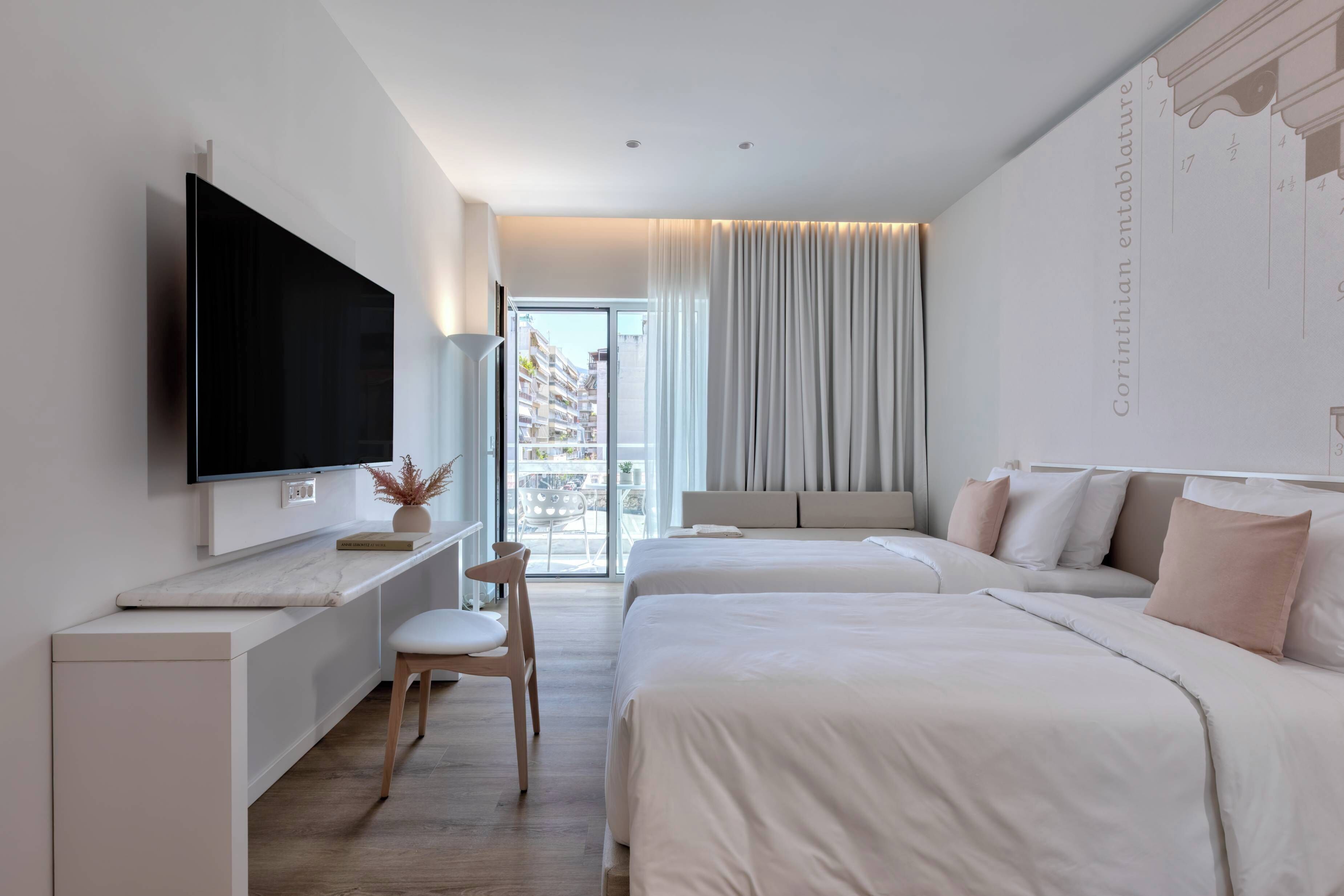 Een moderne hotelkamer met een flatscreen televisie, een bureau met stoel, twee bedden en een balkon met gordijnen.
