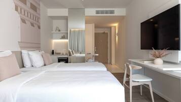 Habitación de hotel moderna con una cama grande, un escritorio, una silla, un televisor y un baño visible a través de una puerta abierta.