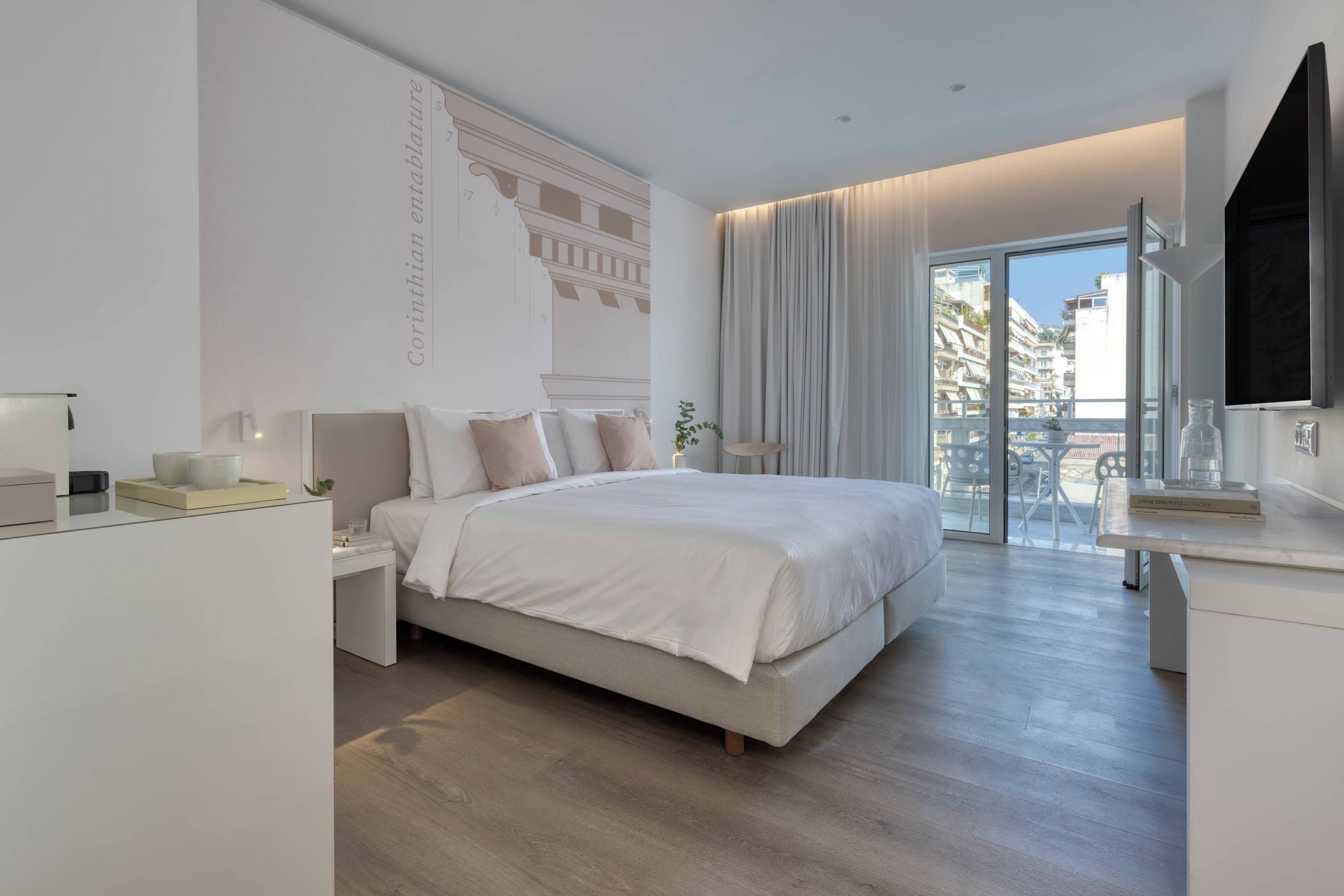 Un dormitorio moderno con una cama grande, una mesita de noche, un escritorio y un balcón con vistas a la ciudad.