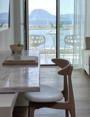 Un interior moderno con vistas al mar, una zona de comedor con mesa y sillas, y un sofá.
