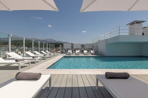 A rooftop pool with lounge chairs and umbrellas, overlooking a mountainous landscape. - Mercure Patras Astir (Patras)