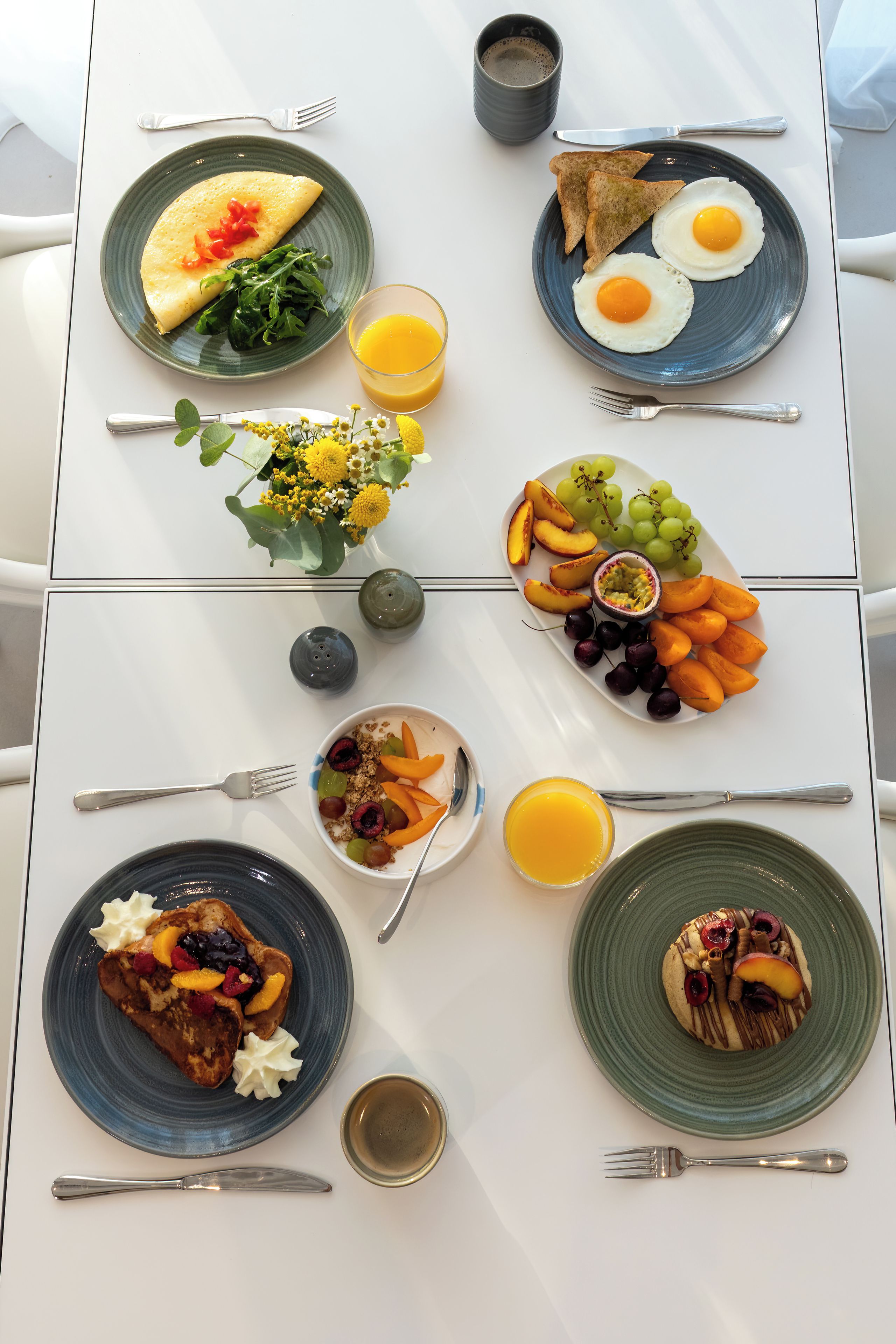 A breakfast table with various dishes including eggs, toast, fruit, and a bowl of cereal.