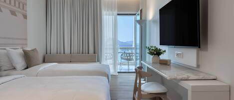 Habitación de hotel con dos camas, un escritorio, una silla, televisión y balcón con vistas.