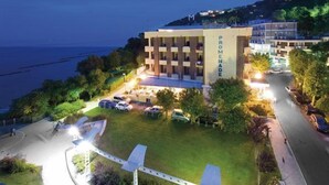 Un hotel con un cartel llamativo que dice "PROMENADE", un estacionamiento y vistas al mar.