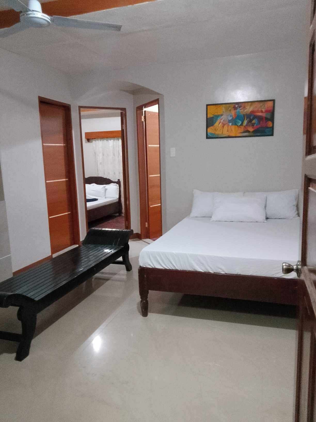 Un dormitorio con cama, un banco y un cuadro en la pared.