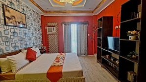 A hotel room with a large bed, a television, a bookshelf, and a patterned wall. - Pagudpud Rinnovati Beach Resort (Pagudpud)