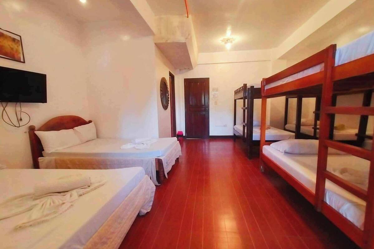 A hotel room with bunk beds, a TV, and a wooden floor.