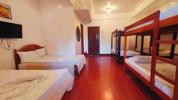 A hotel room with bunk beds, a TV, and a wooden floor.