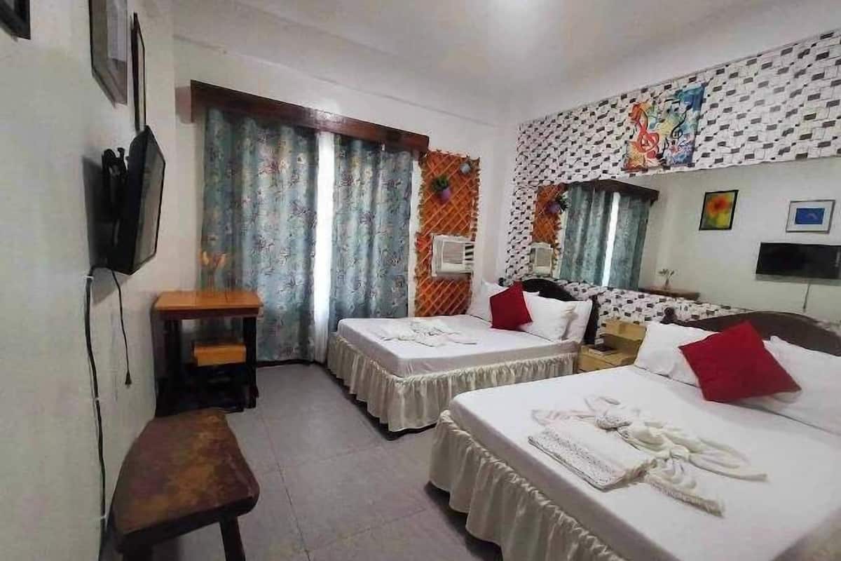 A hotel room with two beds, a desk, a TV, and a window with curtains.