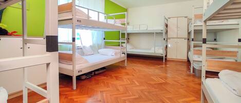 Une chambre de dortoir avec des lits superposés, un plancher en bois et un mur d’accent vert.