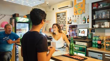 Un bar con mostrador, un refrigerador lleno de bebidas y una pizarra con la carta.