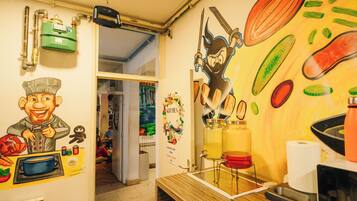 A kitchen with a mural, a green water heater, and a red sink.