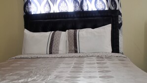 A bed with a patterned bedspread, a black headboard, and two pillows. - Nairobi Transit Lounge (Syokimau)