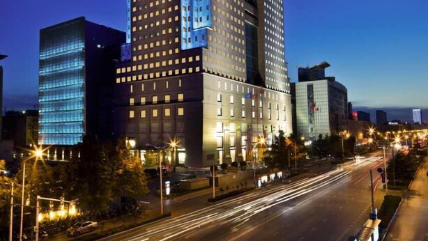 Un hotel modern i de grans edificis, amb un element vertical destacat i una sèrie de finestres il·luminades.