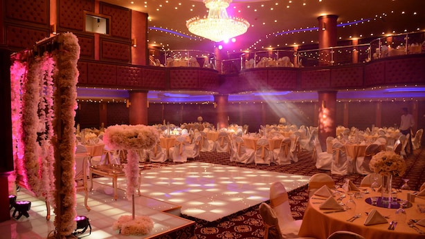 A ballroom with a dance floor, tiered seating, and chandeliers. - Rojina Hotel (Amman)