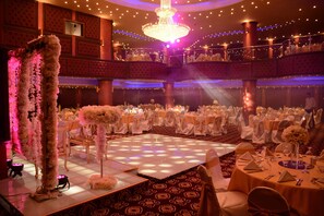 A ballroom with a dance floor, tiered seating, and chandeliers. - Rojina Hotel (Amman)