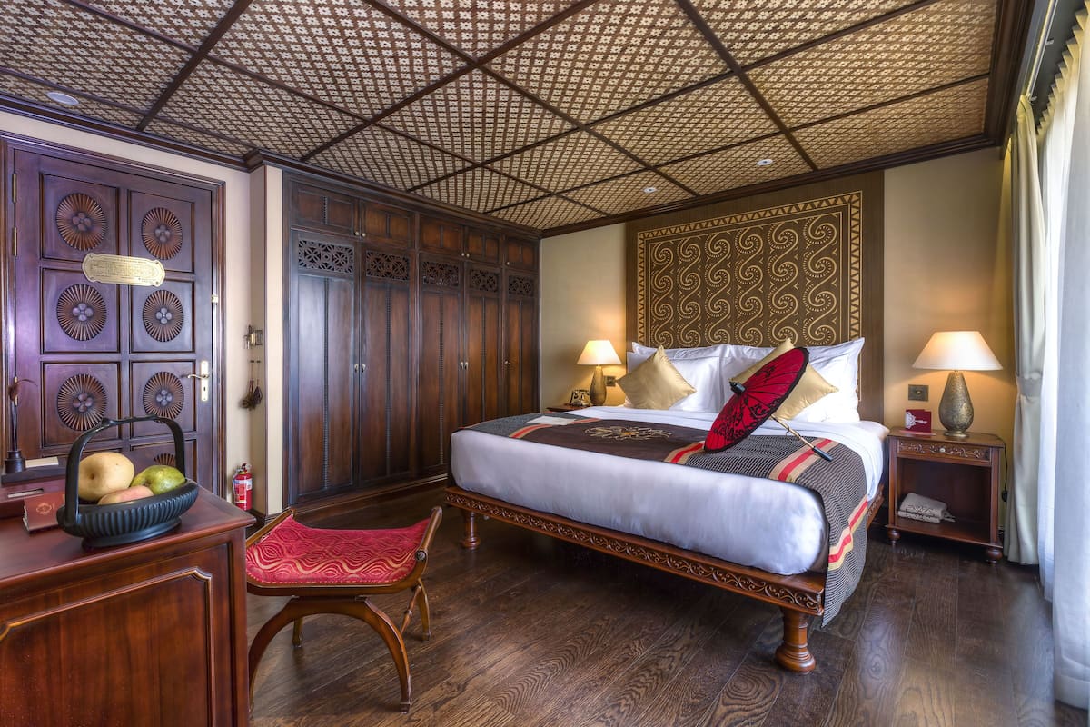Ein traditionell eingerichteter Raum mit einem großen Bett, Holzmöbeln und einer gemusterten Decke.