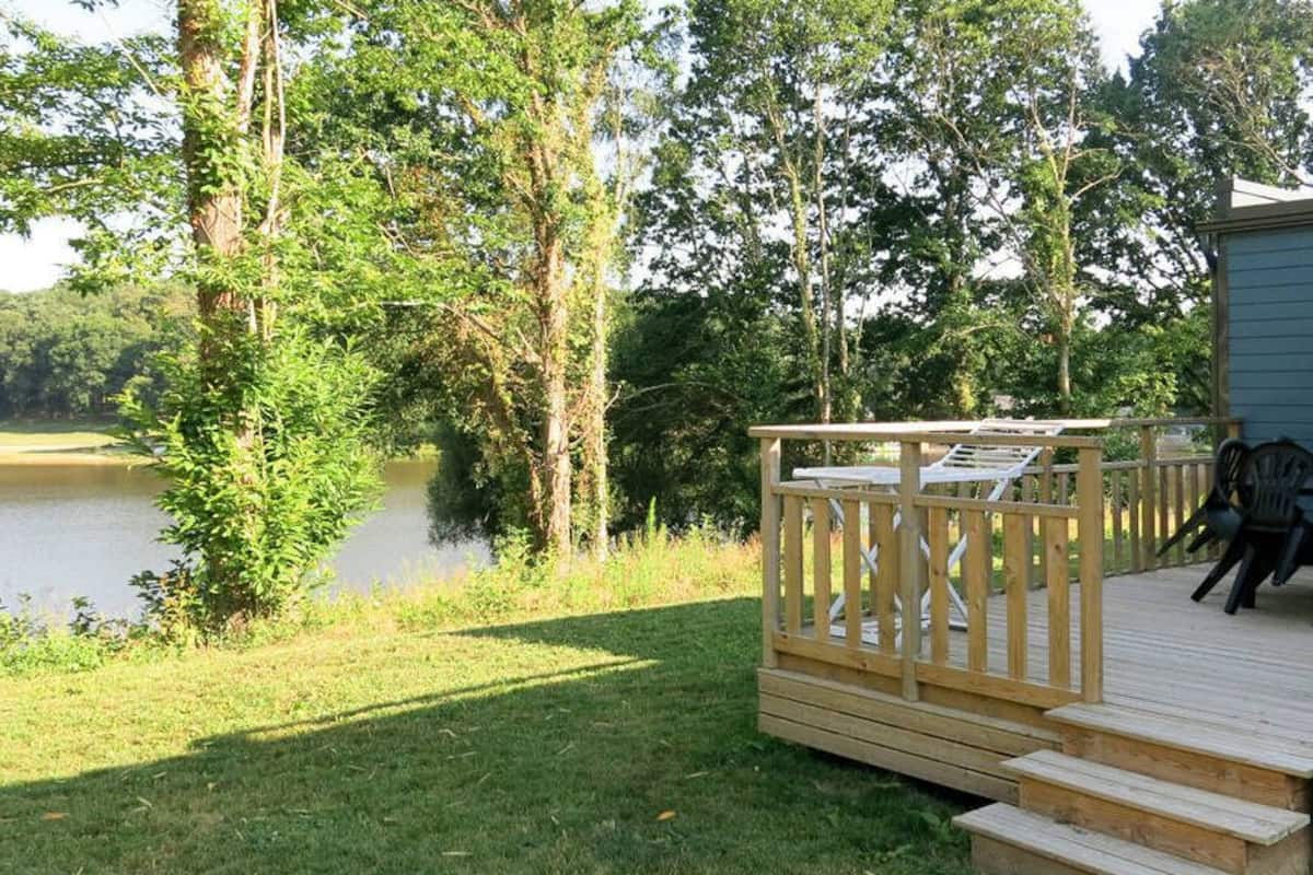 Eine Holzterrasse mit Blick auf einen See und Bäume.