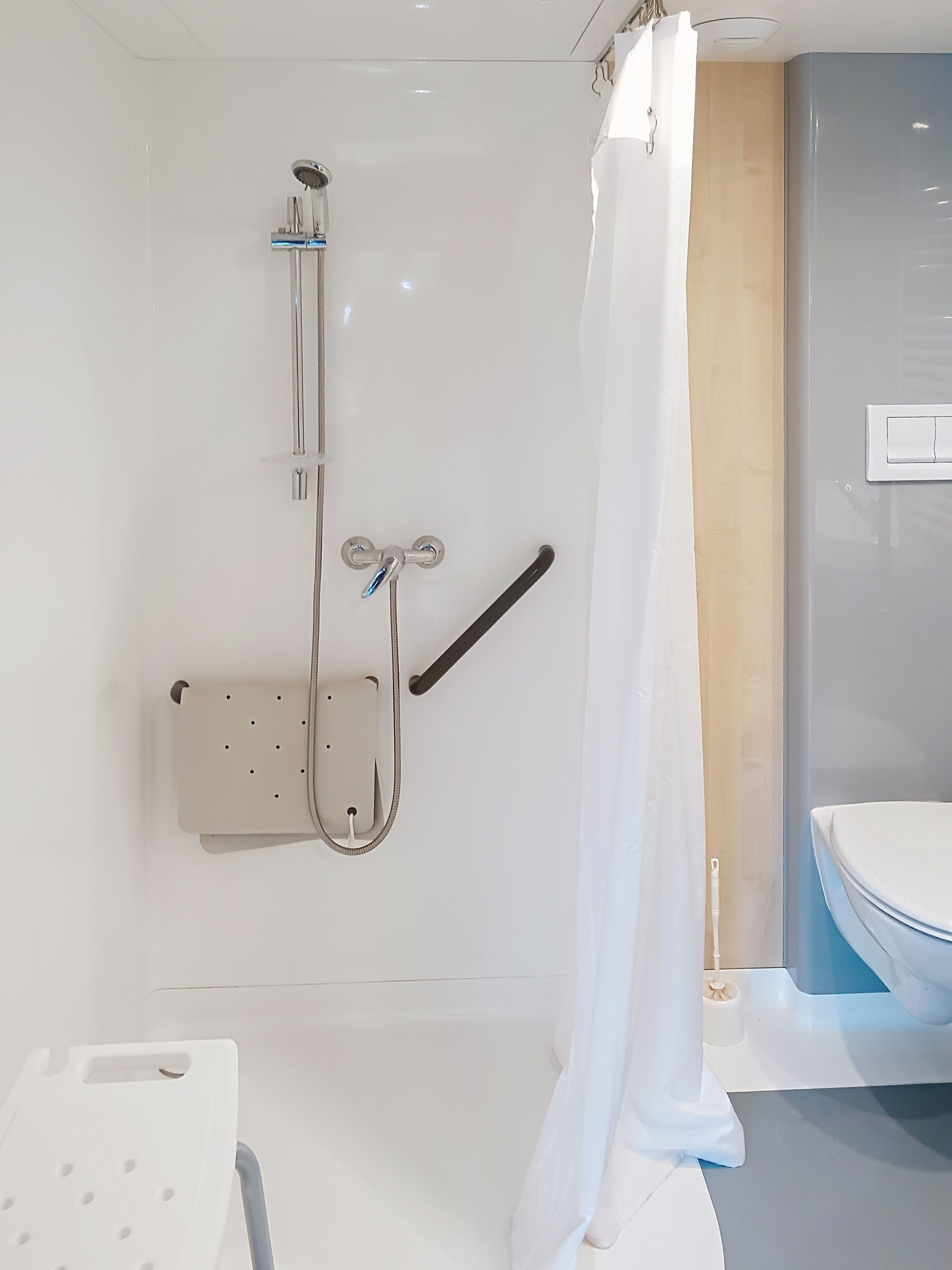 Une salle de bain équipée d’une douche, de toilettes et d’une barre d’appui.