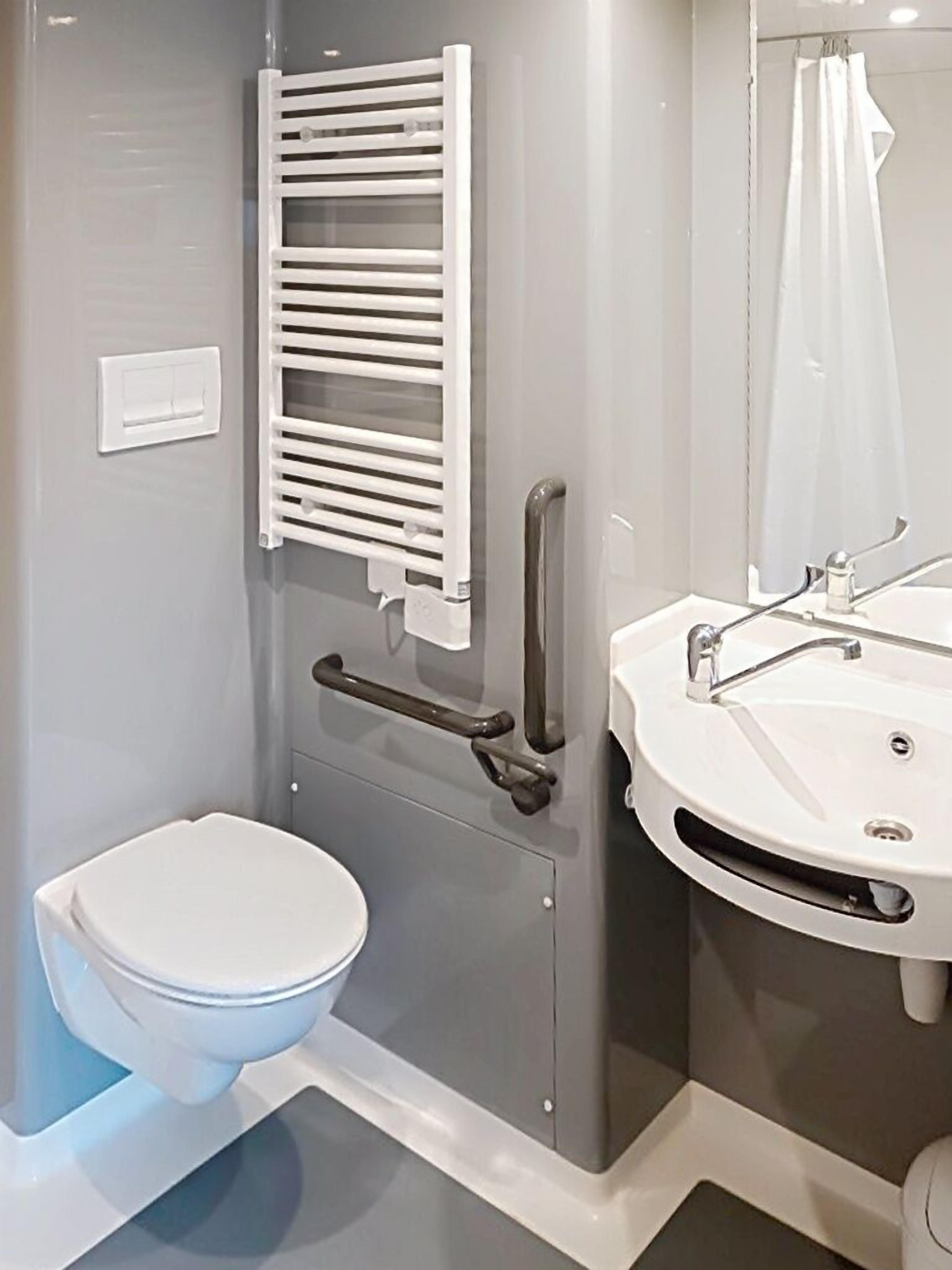 Un baño con inodoro, lavamanos, cortina de ducha y toallero.