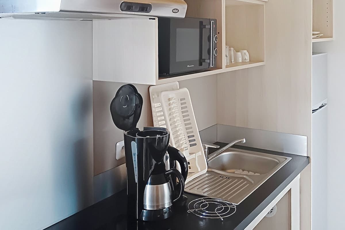 Eine moderne Küche mit schwarzem Arbeitsplatz, einer Kaffeemaschine, einer Mikrowelle und einem Wasserkocher.