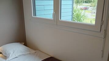 Una habitación pequeña con cama individual y ventana con vistas a un jardín.