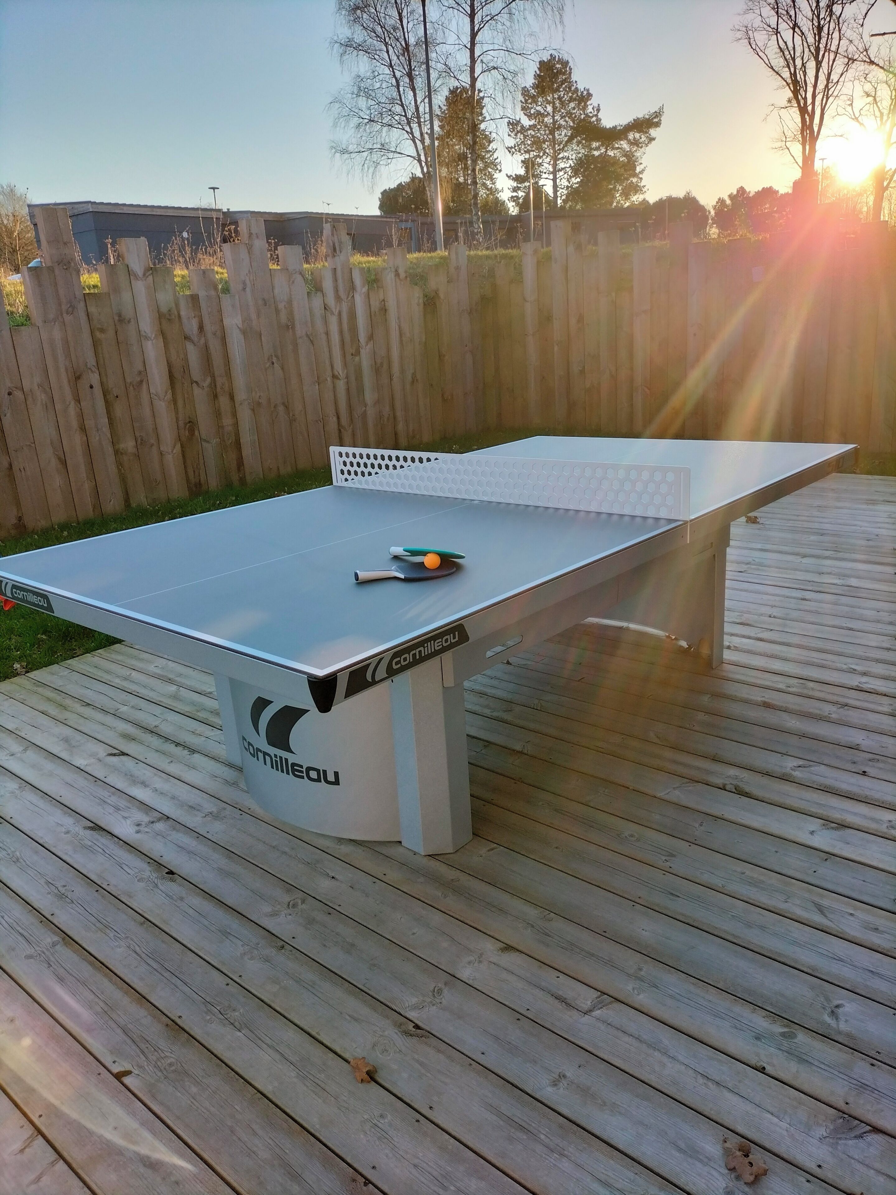 Un tavolo da ping pong con rete, posizionato su un pontile di legno.
