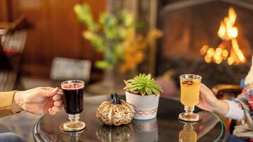 A cozy indoor setting with a glass table, two drinks, a decorative pumpkin, and a potted plant.
