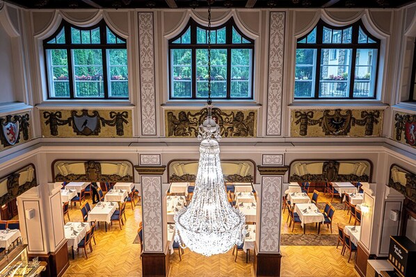 A grand dining hall with ornate chandeliers, large windows, and detailed wall decorations. - Hotel Palota Lillafüred (Miskolc)