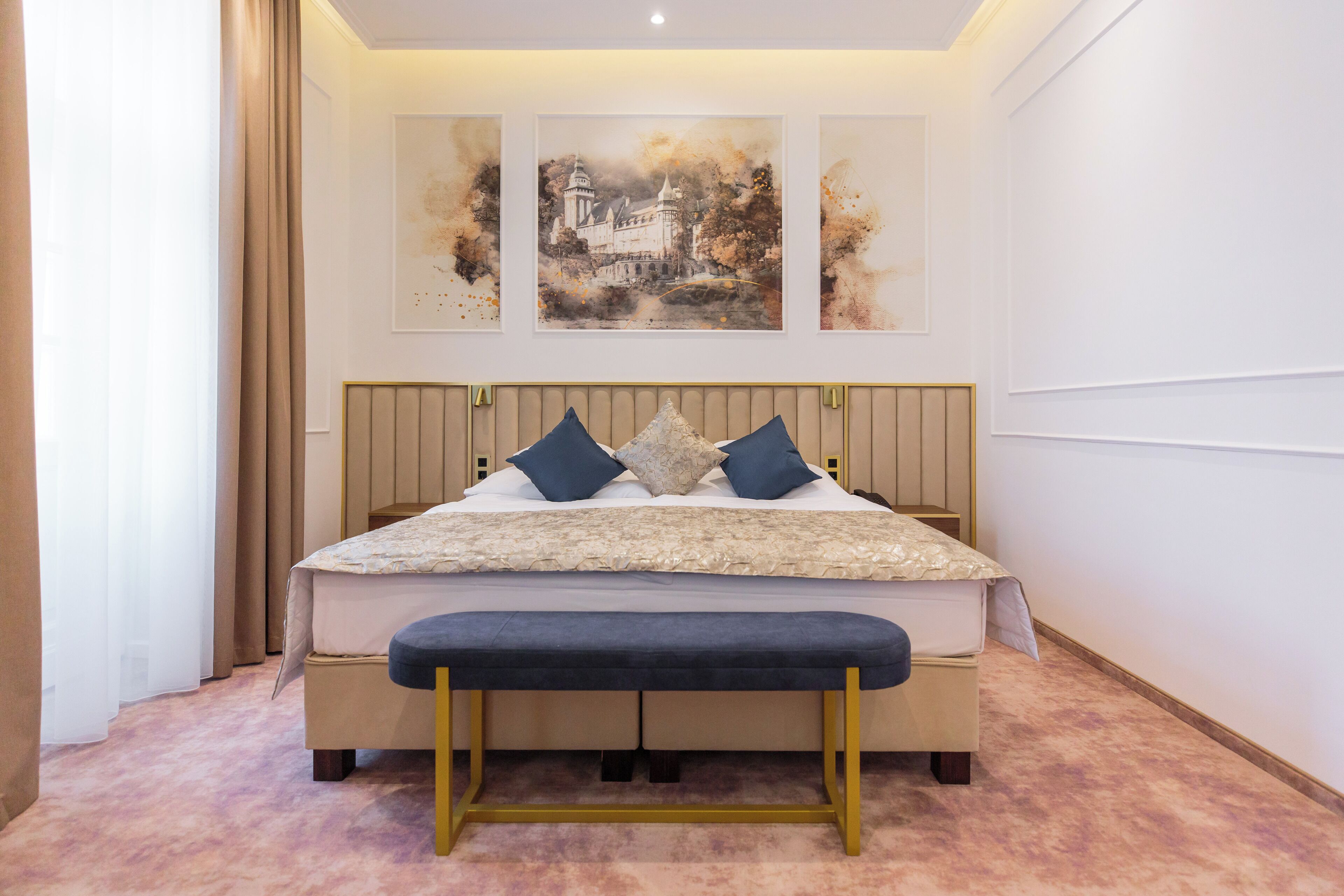 A bedroom with a bed, bench, and three wall-mounted artworks.
