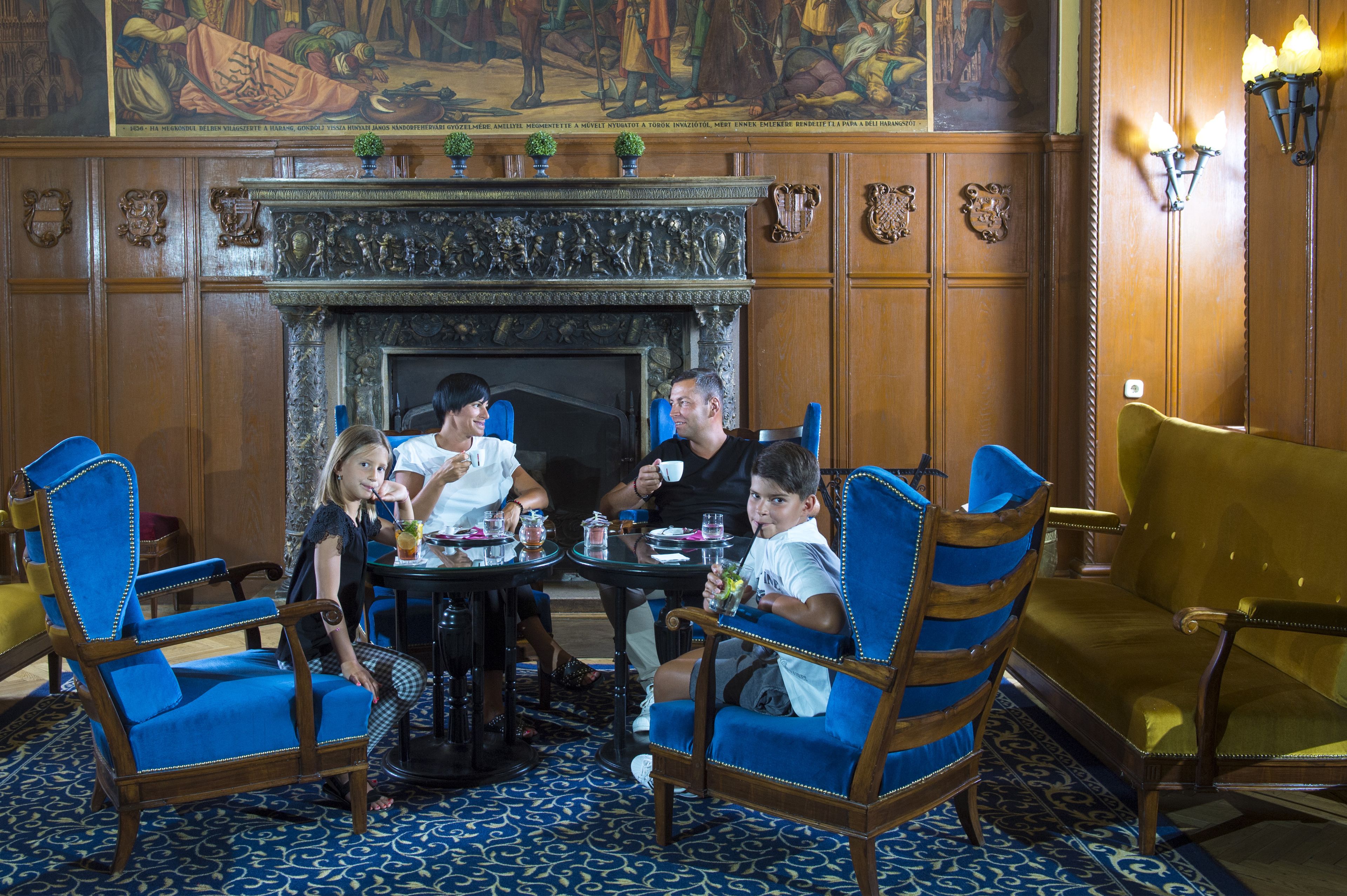 A dining area with a round table, blue upholstered chairs, and a fireplace.