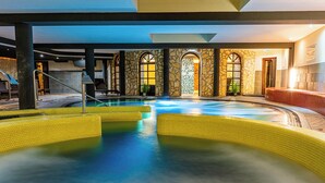 An indoor swimming pool with a stone wall and arched windows. - Hotel Palota Lillafüred (Miskolc)