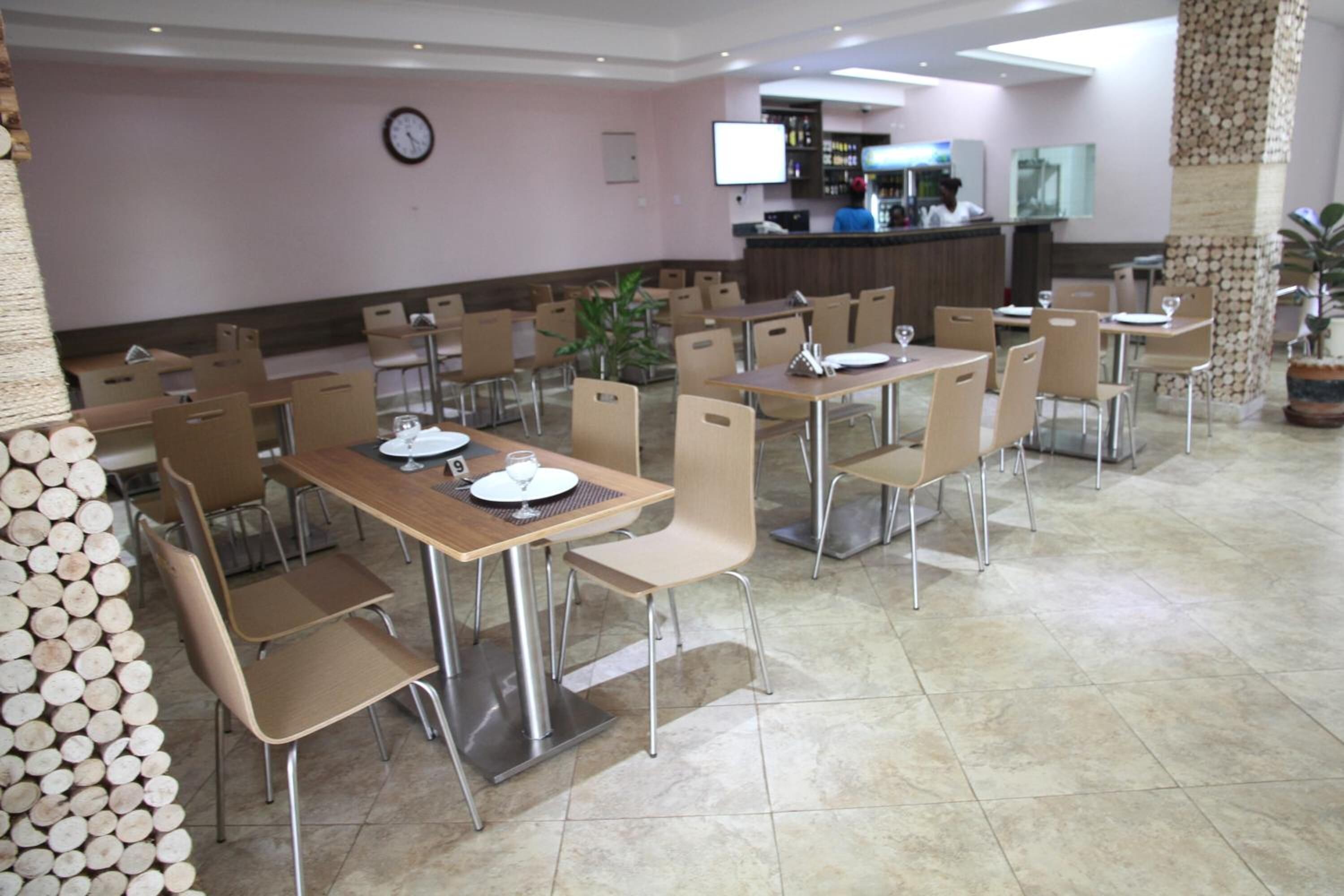 A dining area with multiple tables and chairs, a reception desk, and a clock on the wall.