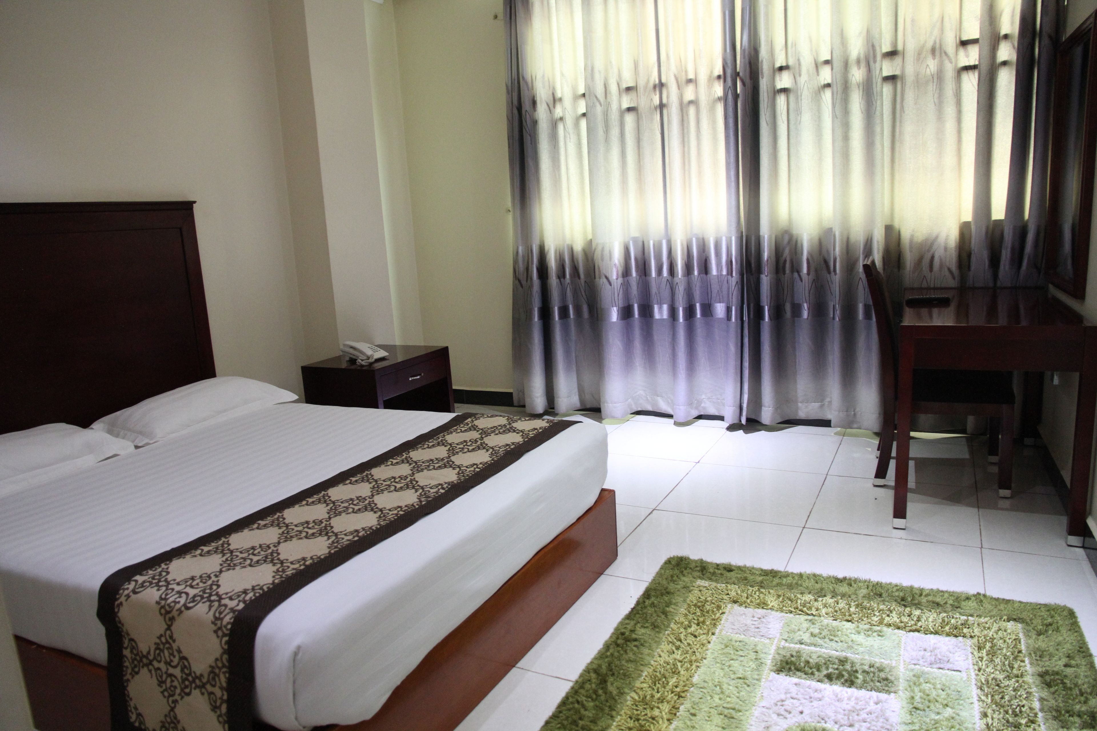 A hotel room with a bed, a desk, and a chair.