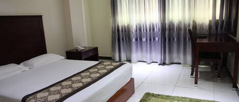 A hotel room with a bed, a desk, and a chair.