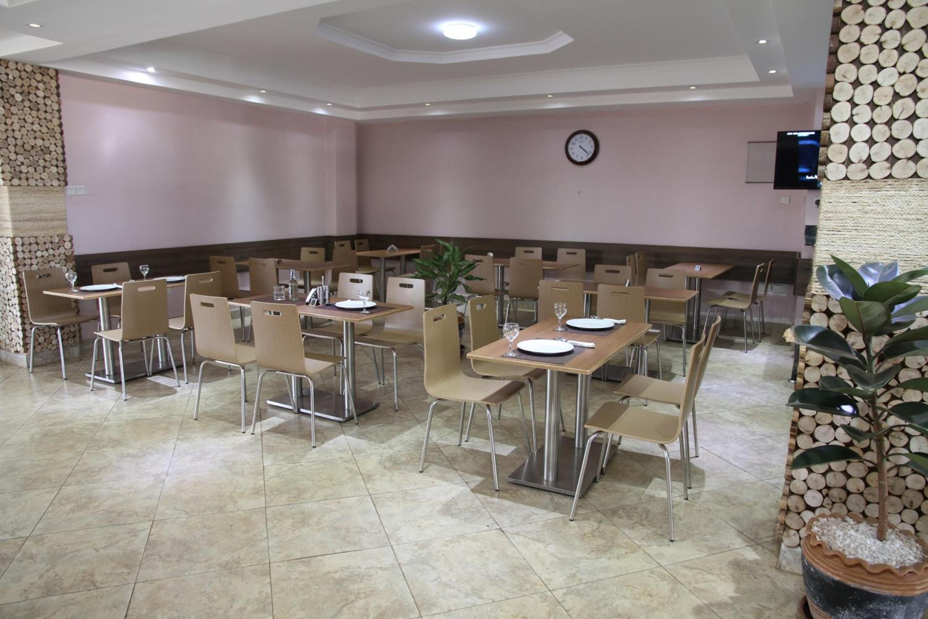 A conference room with multiple tables and chairs, a clock on the wall, and a television screen.