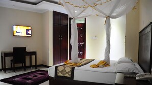 A hotel room with a bed, a desk, a TV, and a wardrobe. - Namayiba Park Hotel (Kampala)
