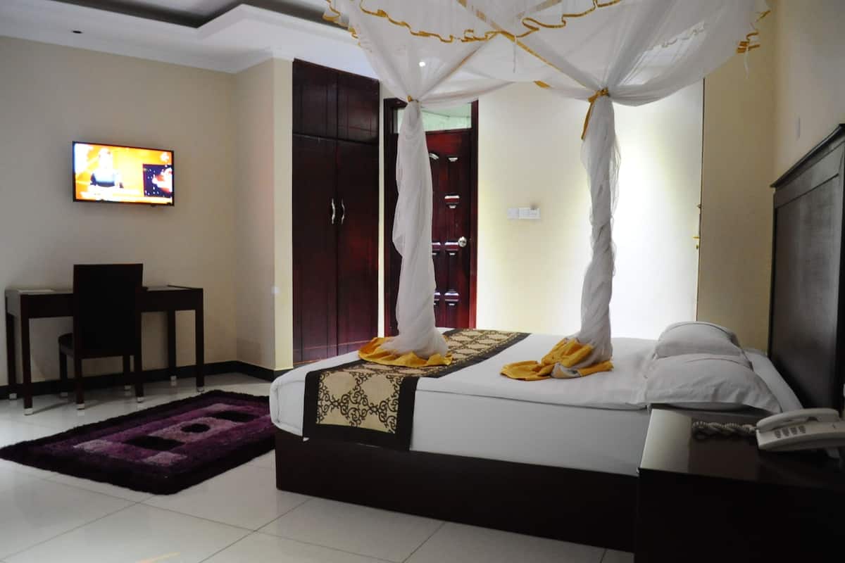 Habitació d'hotel amb llit, escriptori, televisió i armari.