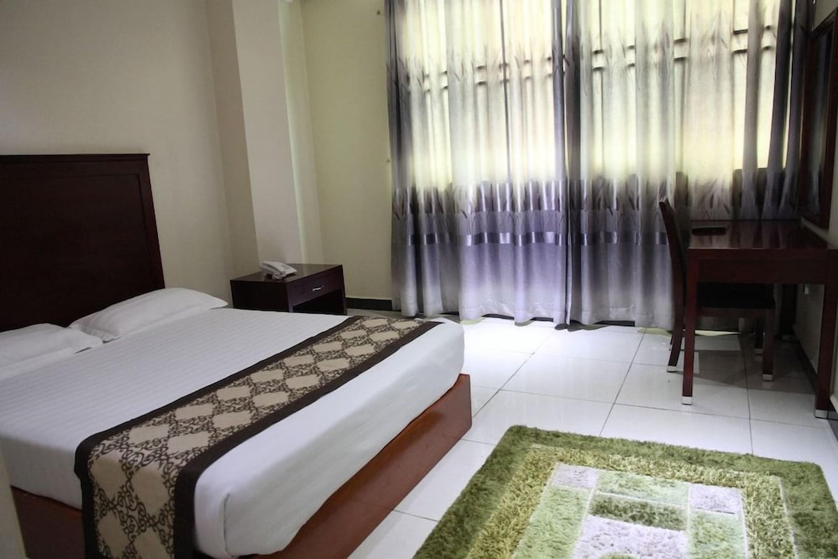 Une chambre d’hôtel avec un lit, un bureau et une chaise.