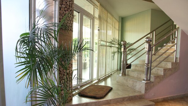 A staircase with a metal railing, a potted plant, and a doormat. - Namayiba Park Hotel (Kampala)